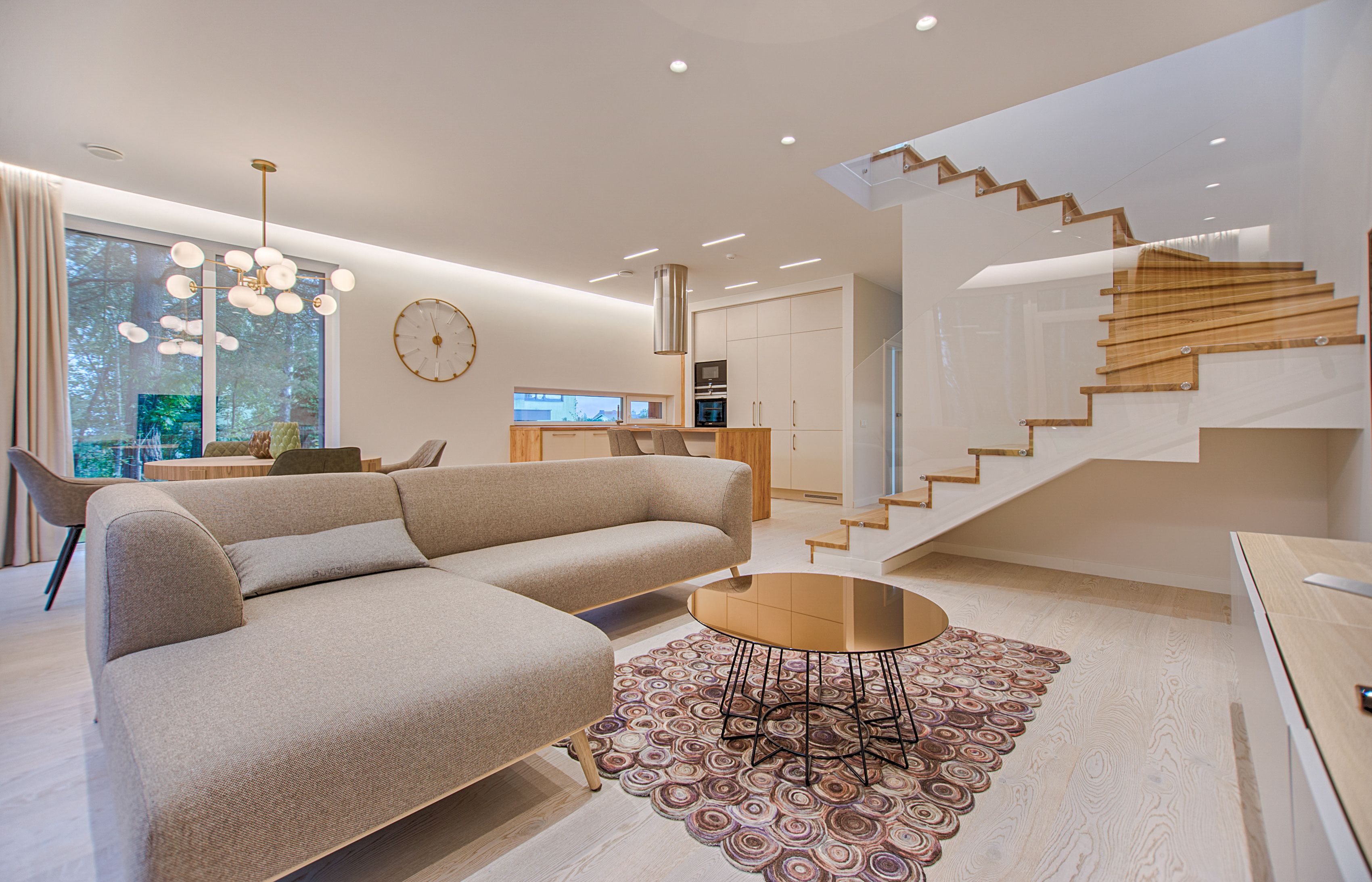 Светъл open-plan интериор с мека мебел, стълба и кухня в една композиция